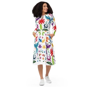 May include: A white midi dress with a colourful floral and animal print. The dress has long sleeves and pockets.
