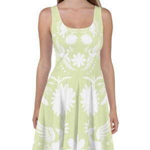 Puede incluir: Un vestido verde claro sin mangas con un estampado floral blanco. El vestido tiene un corpiño ajustado y una falda acampanada.