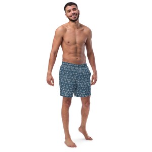 May include: A man wearing blue swim trunks with a white pattern. The trunks have an elastic waistband and a drawstring.