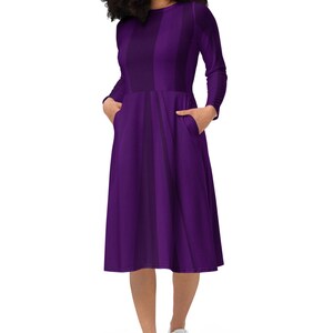 May include: A purple midi dress with vertical stripes. The dress has long sleeves and pockets on the sides.