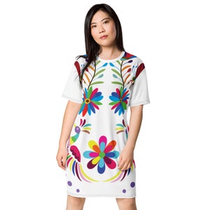 Puede incluir: Un vestido de camiseta blanca con un diseño floral y de pájaros colorido. El diseño presenta colores brillantes como rojo, amarillo, azul, verde y morado.