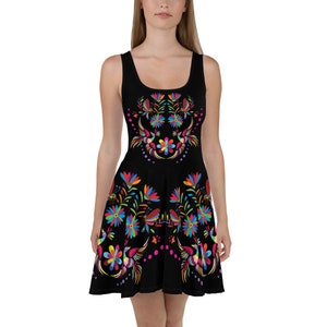 Puede incluir: Un vestido skater negro con un diseño floral y de pájaros colorido. El vestido tiene un escote redondo y es sin mangas.