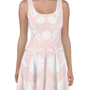 Puede incluir: Un vestido skater rosa con un estampado floral blanco. El vestido tiene un escote redondo y es sin mangas.