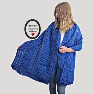 May include: A royal blue crochet cardigan featuring a textured bobble stitch pattern, long sleeves, and an open front design. A black oval graphic on the left includes the white text 40% off on 2 or more patterns with a small red heart icon.