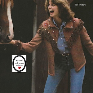 May include: A brown knit jacket featuring long fringe detailing across the chest and shoulders, accented with small colorful studs. The jacket is worn over a light blue button-down shirt and blue jeans. Text reads PDF Pattern.