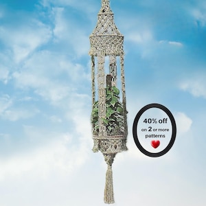 May include: A beige macrame plant hanger featuring intricate knotted patterns, a central cylindrical structure holding a green leafy plant, and a long decorative tassel at the bottom. A black oval badge displays the text 40% off on 2 or more patterns.