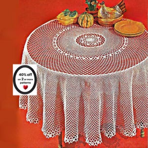 Può includere: Una tovaglia rotonda in uncinetto bianco con un delicato motivo a rete traforata e un bordo smerlato. Un piccolo cartello sulla sinistra mostra il testo 40% off on 2 or more patterns con un'icona a forma di cuore rosso.
