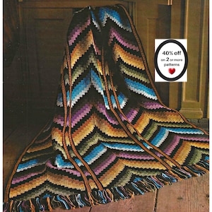 Peut inclure: Une couverture crochetée avec un motif en chevron dans des fils noirs, bleus, violets, dorés et verts. La couverture présente un bord à franges et des rayures texturées verticales. Un panneau blanc affiche le texte 40% off on 2 or more patterns.