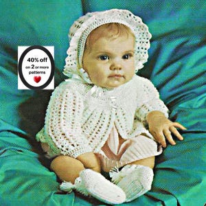 May include: A white crocheted baby set consisting of a long-sleeved cardigan with a scalloped edge, a matching bonnet with a ribbon tie, and a pair of booties. The set features a delicate openwork pattern and is displayed on a teal background.