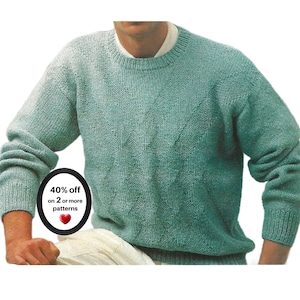 May include: A long-sleeved, crew-neck sweater in a soft seafoam green color, featuring a textured diamond cable knit pattern across the front. The garment has ribbed cuffs and a ribbed neckline, layered over a light-colored collared shirt.