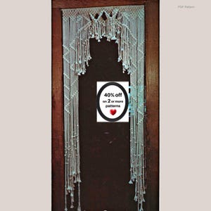 May include: An off-white macrame door hanging featuring intricate knotted patterns, a scalloped top edge, and long vertical fringe strands. A central white sign displays the text 40% off on 2 or more patterns with a red heart icon.