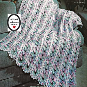May include: A crochet blanket featuring a repeating cable-like chain pattern in variegated shades of teal, lavender, and white. The blanket has a textured surface with vertical columns of interconnected loops. A label reads: 40% off on 2 or more patterns.
