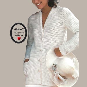 May include: A white long-sleeved cardigan with a textured knit pattern, a collared neckline, and a front button closure. The garment features two front pockets and is paired with a white wide-brimmed hat adorned with floral accents.