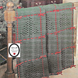 May include: A dark green crocheted blanket featuring a grid pattern created by woven red ribbon. The blanket displays openwork crochet designs in the shape of Christmas trees within each grid section. Small red ribbon bows are tied at each intersection.