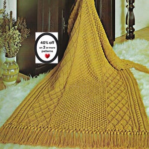 May include: A mustard yellow knitted throw blanket featuring a complex textured pattern of diamonds and vertical cables, finished with long fringe along the bottom edge. A circular graphic overlay displays the text 40% off on 2 or more patterns.