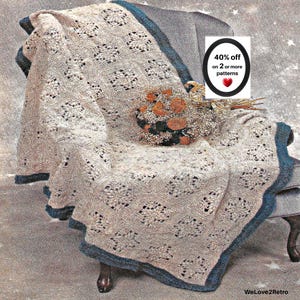 May include: A beige crocheted blanket featuring a repeating square pattern with a dark teal border. The blanket is draped over a chair and includes a small cluster of dried orange and brown flowers. Text on the image reads 40% off on 2 or more patterns.