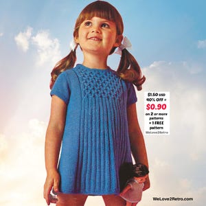 May include: A young girl wearing a blue knitted dress with a textured yoke and vertical ribbing. The dress has short sleeves and is knee-length. The image includes text that says "WeLove2Retro".