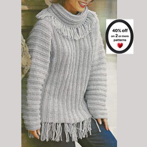 May include: A light gray knit sweater featuring a high cowl neckline with fringe detailing, long sleeves with horizontal ribbed texture, and a vertical ribbed body pattern. The hem is finished with long fringe. Text reads: 40% off on 2 or more patterns.