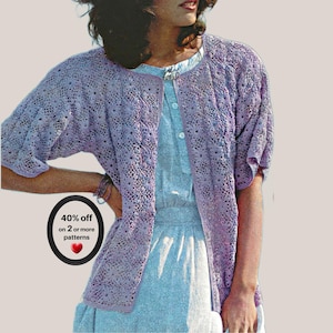 May include: A light purple open-front cardigan featuring an intricate lace knit pattern with short sleeves. The garment is worn over a light blue button-down dress. A black oval graphic on the left displays the text 40% off on 2 or more patterns.