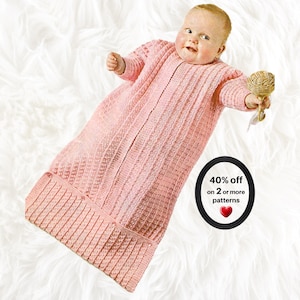 May include: A long-sleeved, light pink knitted baby sleep sack featuring a textured vertical stitch pattern and a ribbed hem. The garment includes a circular black graphic with the text 40% off on 2 or more patterns and a red heart icon.