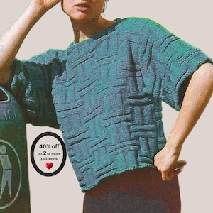 May include: A teal green short-sleeved sweater featuring a textured basketweave pattern. The garment has a round neckline and a boxy fit. A circular black badge on the left side displays the text 40% off on 2 or more patterns with a red heart.