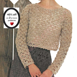 May include: A beige long-sleeved crochet sweater with an openwork pattern and a round neckline. A circular graphic in the corner displays the text 40% off on 2 or more patterns with a red heart icon. The sweater is worn over a dark gray skirt.