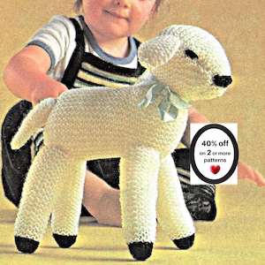 May include: A cream-colored knitted lamb toy with a textured surface, black hooves, and a light green ribbon tied around its neck. A white rectangular sign features the text 40% off on 2 or more patterns with a red heart icon below the text.