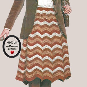Puede incluir: Una falda de ganchillo hasta la rodilla con un patrón de chevrón repetitivo en rayas horizontales alternas de color naranja óxido, tostado y crema. Una insignia circular negra a la izquierda muestra el texto 40% off on 2 or more patterns con un corazón rojo.