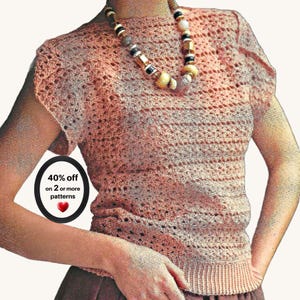 May include: A peach-coloured short-sleeved crochet top with a textured openwork pattern and a ribbed hem. A beaded necklace with gold, black, and white beads rests at the neckline. A circular black badge displays the text 40% off on 2 or more patterns.