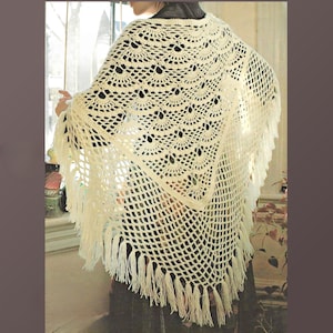 Può includere: Sciarpa all'uncinetto fatta a mano, color crema, con bordo a frange. Lo scialle presenta un design traforato dettagliato con motivi circolari e una base a rete quadrata. Lo scialle è drappeggiato sulle spalle, mostrando la sua trama.