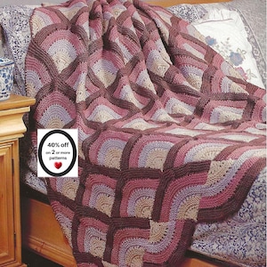 May include: A crocheted blanket featuring a repeating fan-like pattern in shades of dark brown, mauve, and light beige. A white rectangular label is overlaid on the blanket with the text 40% off on 2 or more patterns and a red heart icon.