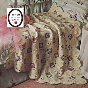 Puede incluir: Una manta de ganchillo color crema con un patrón repetitivo de motivos circulares y pequeños detalles florales cuadrados en rosa y verde. La manta tiene un borde festoneado con ribete verde y el texto 40% off on 2 or more patterns.