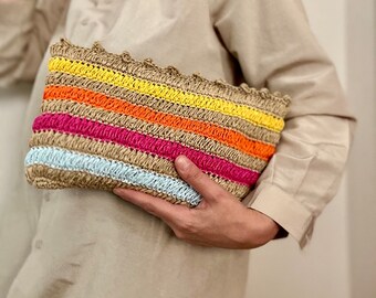 May include: A striped woven clutch bag with a crocheted trim. The bag features alternating stripes of light blue, pink, orange, and yellow.