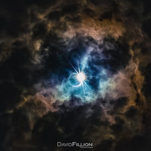 May include: A solar eclipse seen through dark clouds, with a bright ring of light around the sun.