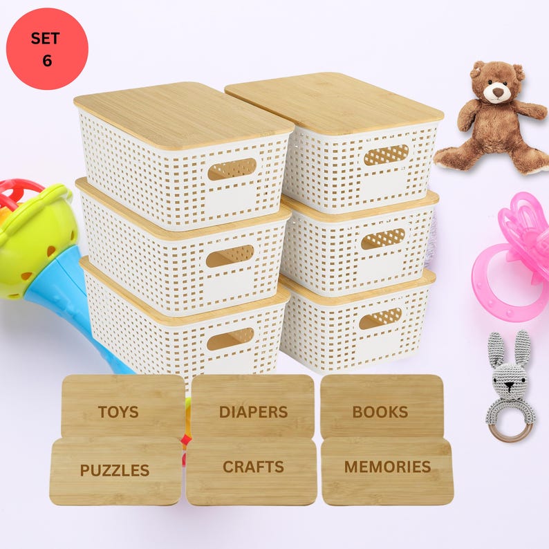May include: A set of six white storage baskets with bamboo lids. Each basket has a rectangular shape with a woven design and handles. The image includes labels for toys, diapers, books, puzzles, crafts, and memories. A teddy bear and baby toys are also present.