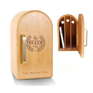 May include: A wooden phone box with a door that opens. The box is decorated with a wreath and the text "the MILLERS family". The box is labeled "The Phone Box".