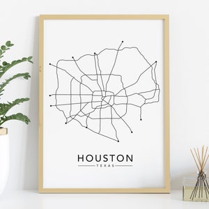 Może przedstawiać: Czarno-biały wydruk liniowy mapy ulic Houston w Teksasie w jasnej drewnianej ramie. Pod mapą znajduje się napis "HOUSTON - TEXAS".