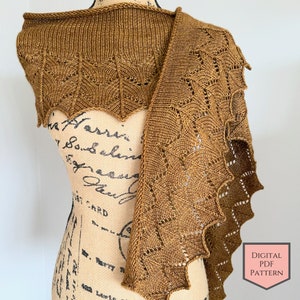 Könnte beinhalten: Ein braunes gestricktes Tuch mit einem Spitzenmuster. Das Tuch ist über eine Schaufensterpuppe gelegt. DIGITAL PDF PATTERN steht in der rechten unteren Ecke des Bildes.