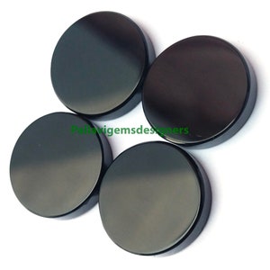 Könnte beinhalten: Vier runde, schwarze Obsidian-Cabochons. Jeder Cabochon ist glatt und poliert, mit einem glänzenden Finish.