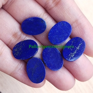 May include: Six oval-shaped lapis lazuli gemstones in various shades of blue. The stones are smooth and polished, with a slight sparkle.