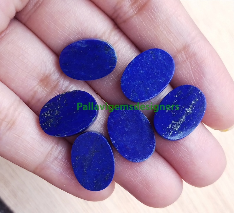 May include: Six oval-shaped lapis lazuli gemstones in various shades of blue. The stones are smooth and polished, with a slight sparkle.