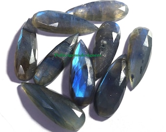May include: A group of eight teardrop-shaped labradorite gemstones with a faceted cut. The stones are a dark gray color with iridescent blue and green flashes.