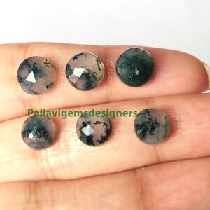 May include: Six round, faceted, green and pink agate cabochons. The stones have a mottled, cloudy appearance with dark green and light pink colors.