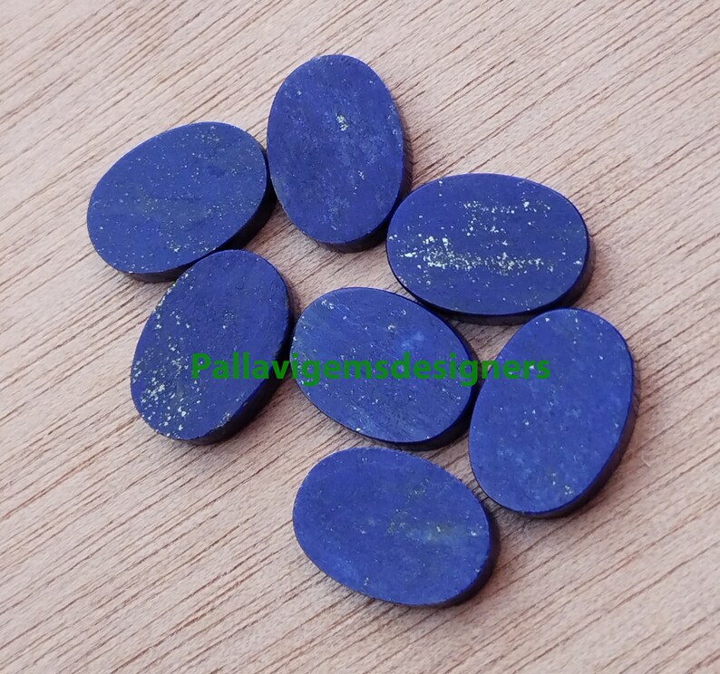 May include: Seven oval-shaped lapis lazuli cabochons, ranging in size, with a deep blue colour and flecks of gold pyrite.