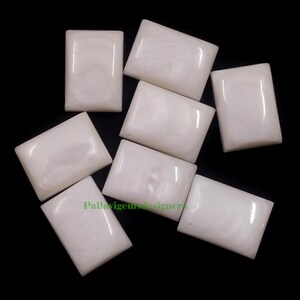 May include: Seven white rectangular mother of pearl cabochons, each with a slightly different iridescent sheen.
