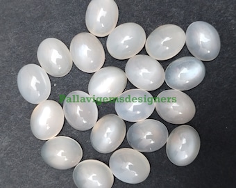 Puede incluir: Una colección de 17 cabujones ovalados de piedra lunar blanca. Las piedras son lisas y pulidas, de color blanco lechoso y con un brillo sutil.
