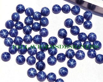 May include: A collection of 30 round, blue star sapphire cabochons. The cabochons are approximately 4mm in diameter and have a star-shaped pattern.
