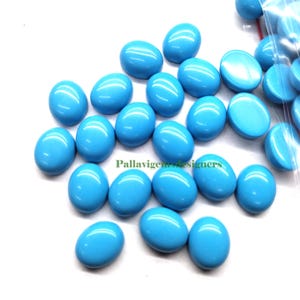May include: A collection of oval-shaped turquoise cabochons, a type of gemstone, in various sizes. The stones are a vibrant blue color and have a smooth, polished finish.