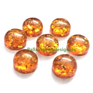 Puede incluir: Siete piedras preciosas redondas de cabujón ámbar con un aspecto translúcido y moteado. Las piedras preciosas miden aproximadamente 10 mm de diámetro.