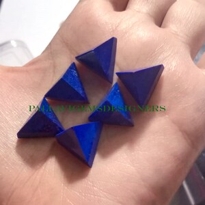 May include: Six blue lapis lazuli pyramid shaped gemstones. The gemstones are faceted and have a polished finish.